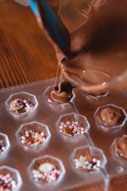 Bild von Schneebesen mit Schokolade für die Kuchenzubereitung süße Kuchenglasur hausgemachter Prozess mit Kakao schmelzen zusammen, um eine Glasur für süßen Kuchen und Schokolade zu schaffen, Nahaufnahme
