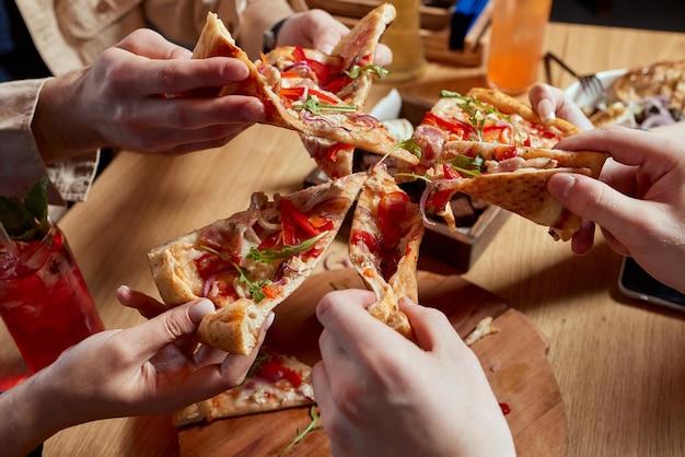 Bild von Teenagerfreunden, die Pizzastücke nehmen