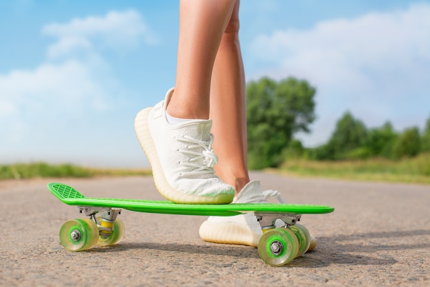 Bild von weiblichen Beinen mit einem Skateboard. Erholungs- und Unterhaltungskonzept. Sport. Gemischte Medien