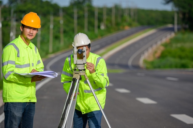 Bild von zwei Bauingenieuren, die Landkoordinaten mit Theodoliten messen, die an Outdoor-Theodoliten auf einer Straßenbaustelle stehen.