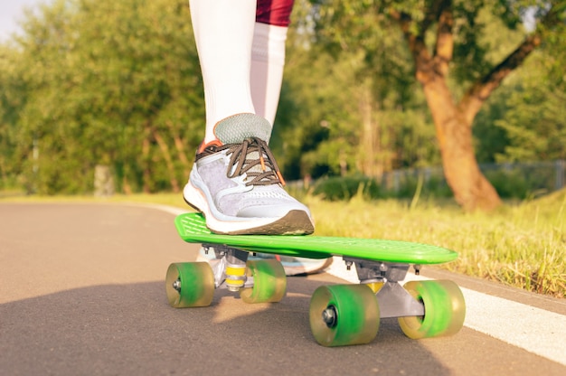 Bilder eines Beins, das auf einem Skateboard steht. Sonniger Abend im Park. Skateboard-Konzept. Gemischte Medien