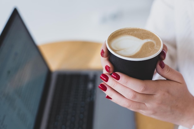 Bilder von Frauenhänden, die eine Papptasse Kaffee halten.