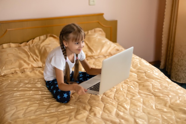 Bildung, Freizeit, Technologie und Internetkonzept - kleines Studentenmädchen mit Laptop-PC zu Hause