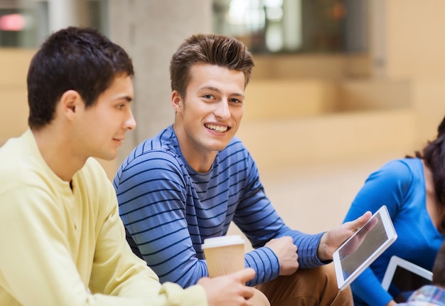 Foto bildung, freundschaft, technologie, getränke und personenkonzept - gruppe lächelnder studenten mit tablet-pc-computern und papierkaffeetasse