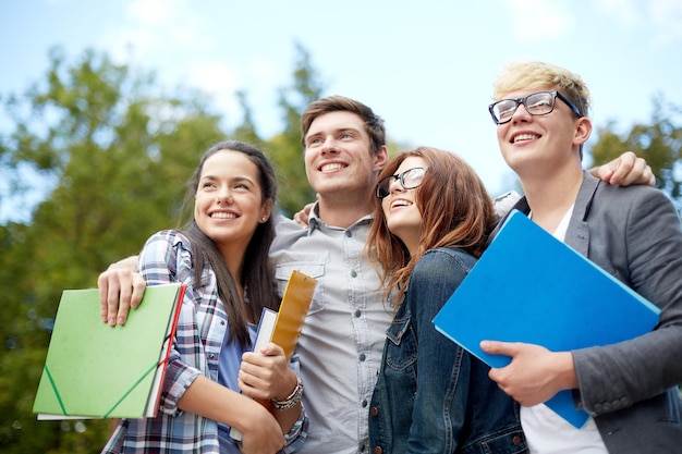 bildung, freundschaft, zukunft und jugendliches konzept - gruppe glücklicher studenten mit ordnern, die auf den campus oder park schauen