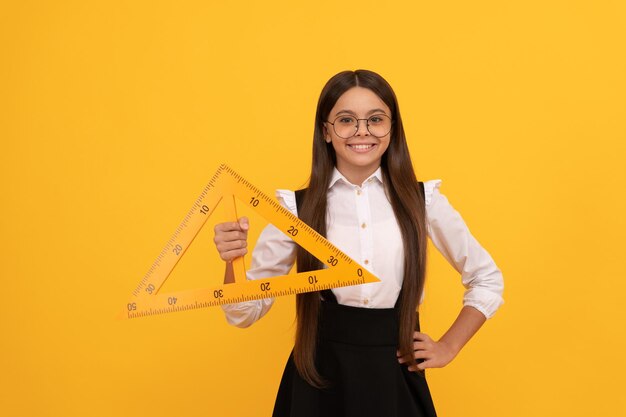 Foto bildung für kinder mathematik lächelndes jugendlich mädchen hält dreieck zurück zur schule