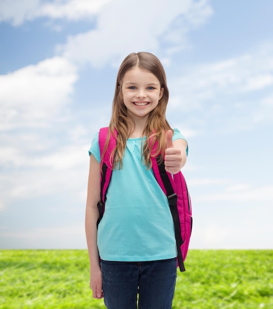 bildung, gesten und schulkonzept - glückliches und lächelndes kleines mädchen mit schultasche, die daumen hoch zeigt