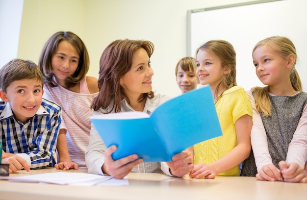 bildung, grundschule, lernen und personenkonzept - gruppe von schulkindern mit lehrer, der im klassenzimmer spricht