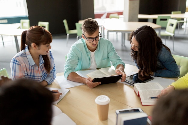 Bildung, Gymnasium, Menschen und Technologiekonzept - Gruppe internationaler Studenten, die mit Tablet-PC-Computern, Büchern und Notizbüchern an der Universität am Tisch sitzen