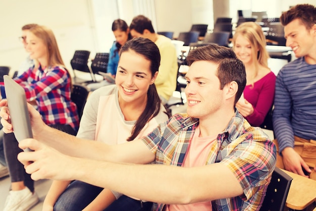 Bildung, Gymnasium, Teamarbeit und People-Konzept - Gruppe lächelnder Studenten mit Tablet-PC-Computern, die im Hörsaal Fotos oder Videos machen