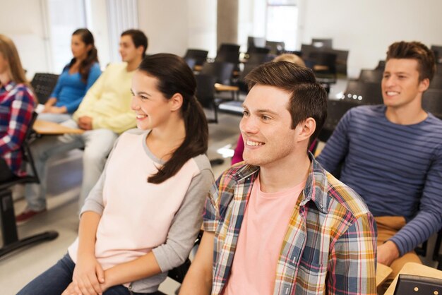 Bildung, Gymnasium, Teamwork und People-Konzept - eine Gruppe lächelnder Studenten, die im Hörsaal sitzen