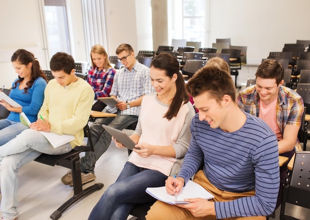 Bildung, High School, Teamwork und People-Konzept - Gruppe lächelnder Studenten mit Tablet-PC-Computern, die im Hörsaal sitzen