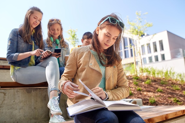 Foto bildung, high school und people-konzept - high-school-studentin liest buch im freien