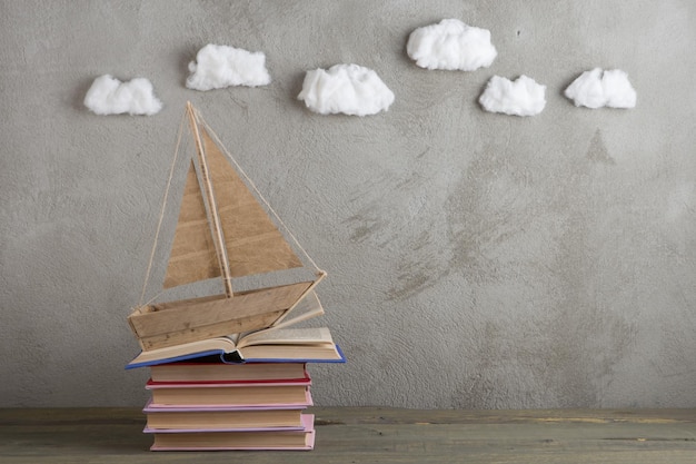 Bildung ist ein Reisekonzept, Spielzeugboot und Bücher wie Meereswellen auf dem Holztisch, Inspiration für das Schreiben eines Märchens