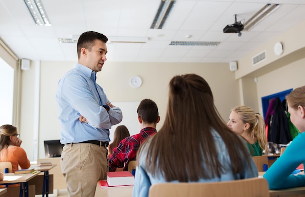 bildung, schule, lernen, lehren und personenkonzept - gruppe von schülern und lehrern, die im klassenzimmer sprechen