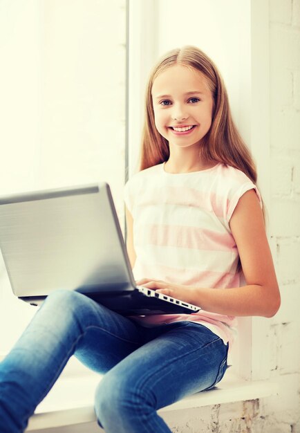 Foto bildung, schule, technologie und internetkonzept - kleine schülerin mit laptop-pc in der schule