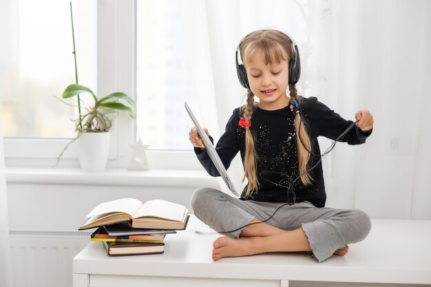 Bildung, Schule, Technologie und Internetkonzept - kleines Studentenmädchen mit Tablet-PC zu Hause