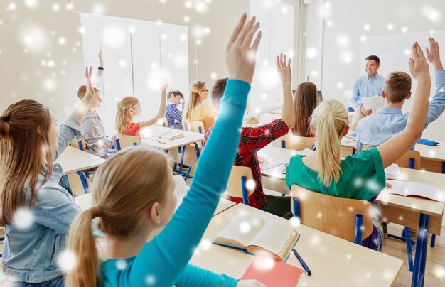 Foto bildung, schule und menschen konzept - gruppe von schülern heben die hände und lehrer mit papieren oder tests über schnee