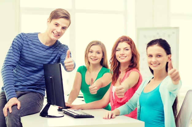 bildung, technologie, schule und personenkonzept - gruppe lächelnder schüler, die im computerunterricht in der schule daumen hoch zeigen