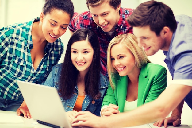 Bildung und Internet - lächelnde Studenten, die sich in der Schule einen Tablet-PC ansehen