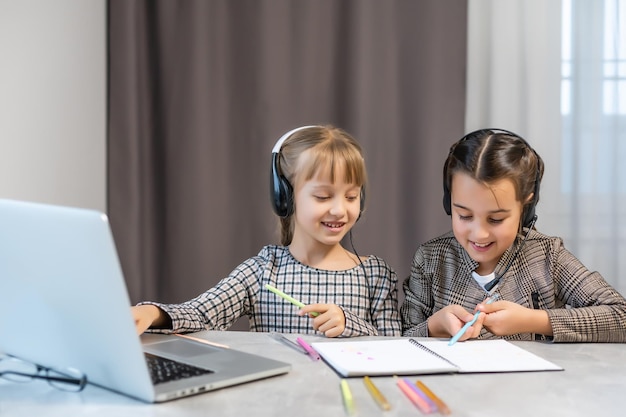 Bildung zu Hause Konzept - zwei süße kleine verspielte Mädchen, die lernen, Hausaufgaben auf dem Laptop zu machen