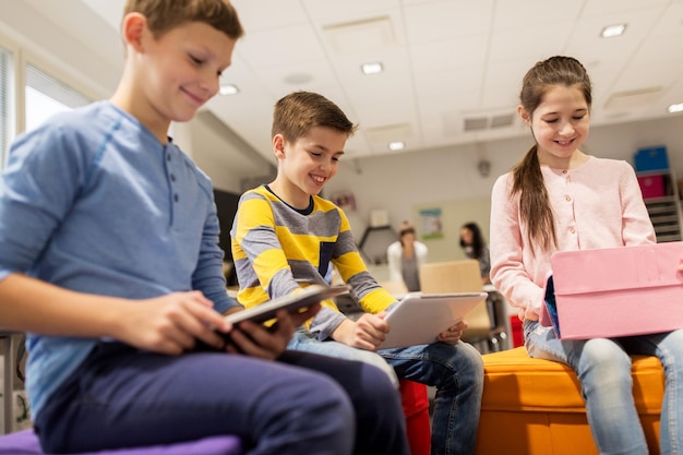 Bildungs-, Kinder-, Technologie- und Menschenkonzept - Gruppe glücklicher Kinder mit Tablet-PC-Computern, die in der Schule lernen