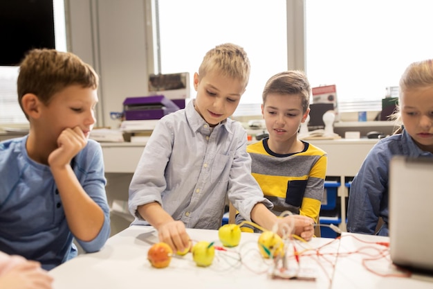 Bildungs-, Kinder-, Technologie-, Wissenschafts- und Menschenkonzept - Gruppe glücklicher Kinder mit Laptop-Computer-Spiel und Erfindungsausrüstung im Robotik-Schulunterricht