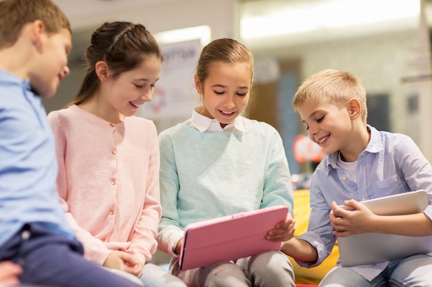 Bildungs-, Kinder- und Menschenkonzept - Gruppe glücklicher Kinder mit Tablet-PC-Computer, die in der Schule lernen