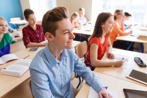 bildungs-, lern- und personenkonzept - gruppe von schülern mit notizbüchern im schulunterricht