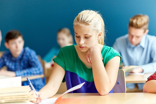 Foto bildungs-, lern- und personenkonzept - gruppe von studenten mit büchern, die schultests schreiben