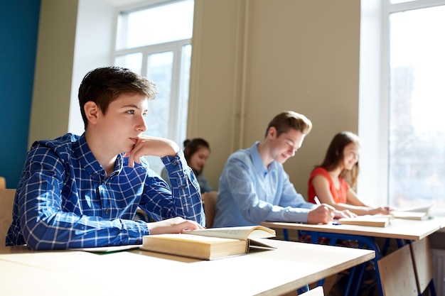 bildungs-, lern- und personenkonzept - gruppe von studenten mit büchern, die schultests schreiben