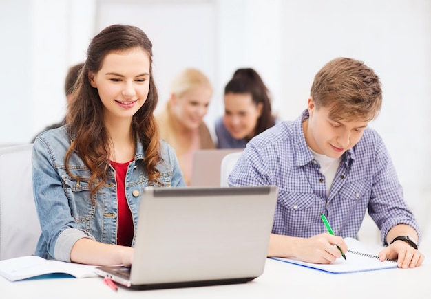 Bildungs-, Technologie- und Internetkonzept - zwei lächelnde Schüler mit Laptop und Notebooks in der Schule