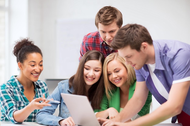 Bildungs- und Internetkonzept - Gruppe internationaler Schüler, die Laptop in der Schule betrachten