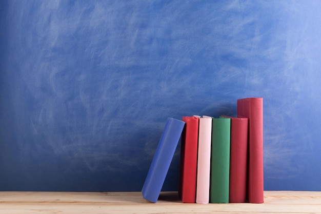 Bildungs- und Lesekonzept Gruppe von Büchern auf der blauen Tafel des Holztischs Lehrerschreibtisch