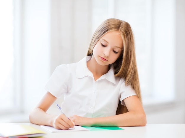 Bildungs- und Schulkonzept - kleine Schülerin, die in der Schule studiert