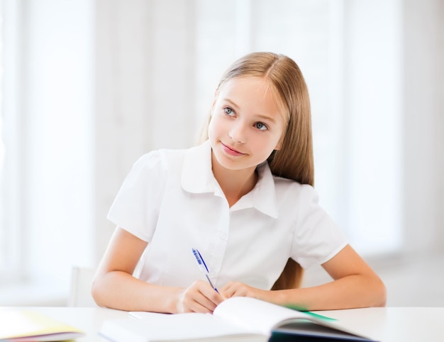 Bildungs- und Schulkonzept - kleine Schülerin, die in der Schule studiert