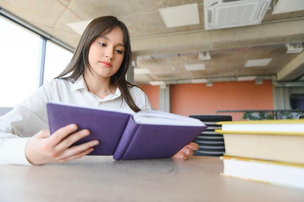 Bildungs- und Schulkonzept-Studentin, die in der Schule ein Buch studiert und liest