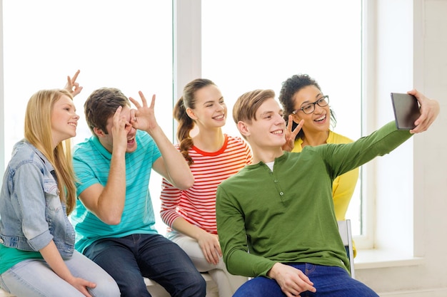 bildungs- und technologiekonzept - lächelnde schüler, die in der schule ein bild mit einem tablet-pc-computer machen