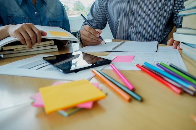 Bildungskonzept Studenten studieren und Brainstorming Campus-Konzept. Nahaufnahme von Studenten diskutieren ihr Thema auf Bücher Lehrbücher und Schreiben an Notebook. Selektiver Fokus