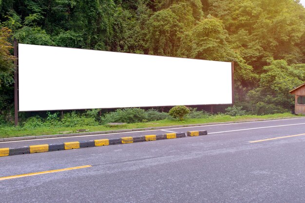 Foto billboard an einer leeren straße gegen bäume und pflanzen