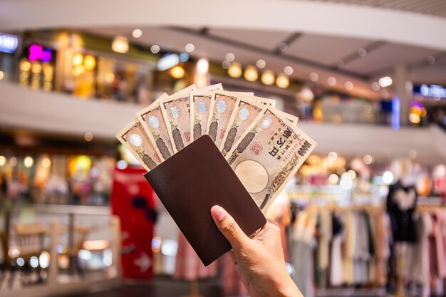 Foto billete de 10.000 yenes japonés en la mano y pasaporte turístico utilizado para comprar y vender mercancías fondo de máscara de demonio tradicional seleccione el enfoque