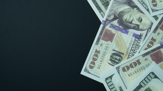 El billete de 100 dólares sobre fondo negro para contenido empresarial