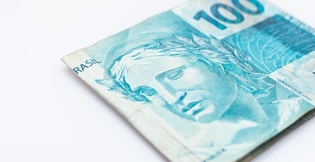 Un billete de 100 reales de moneda brasileña aislado sobre fondo blanco.