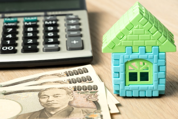 Foto billete de banco japonés, rompecabezas de casa de juguete y calculadora