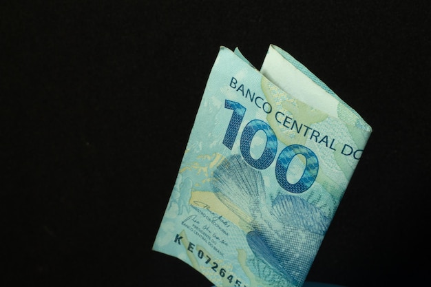 Billete brasileño de cien reales con fondo negro