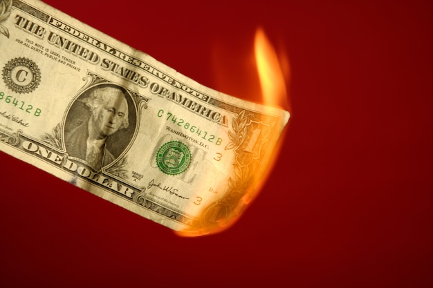 Foto billete de dólar ardiendo en fuego sobre rojo