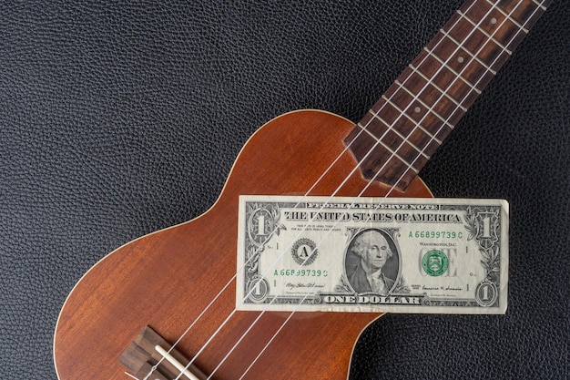 Un billete de un dólar está atascado en un ukelele.