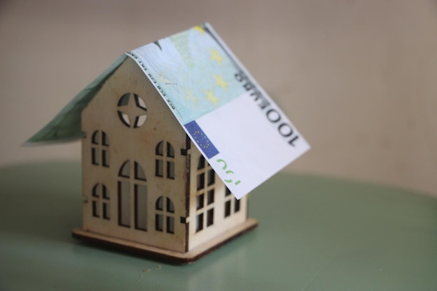 Billete de euro como techo en casa de juguete de madera Seguro de casa o concepto de hipoteca