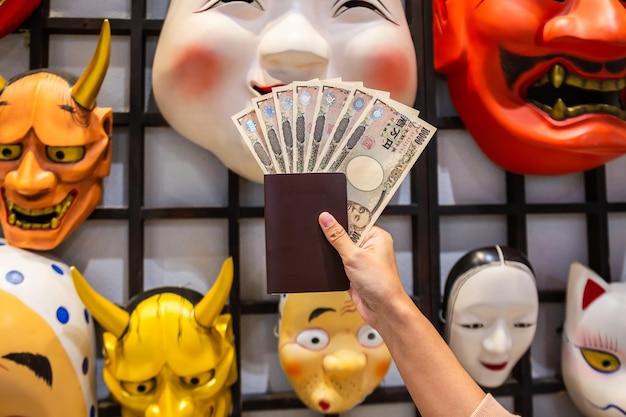 Un billete japonés de 10000 yenes en la mano y un pasaporte turístico se utilizan para comprar y vender mercancías en el fondo de una tienda Seleccione el enfoque