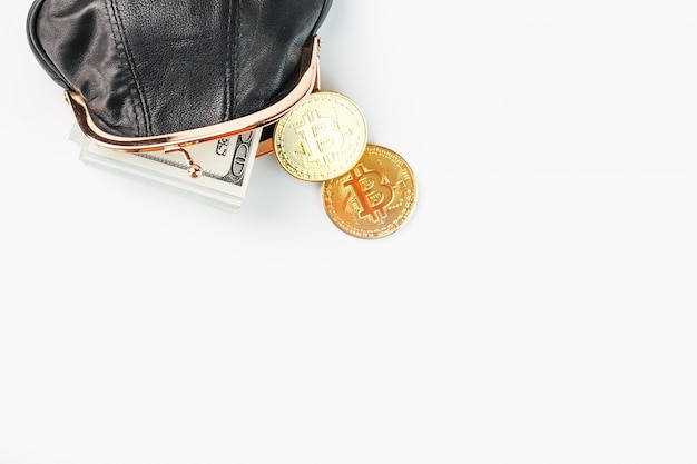Una billetera negra abierta con dinero, dólares y monedas bitcoin en una pared blanca.